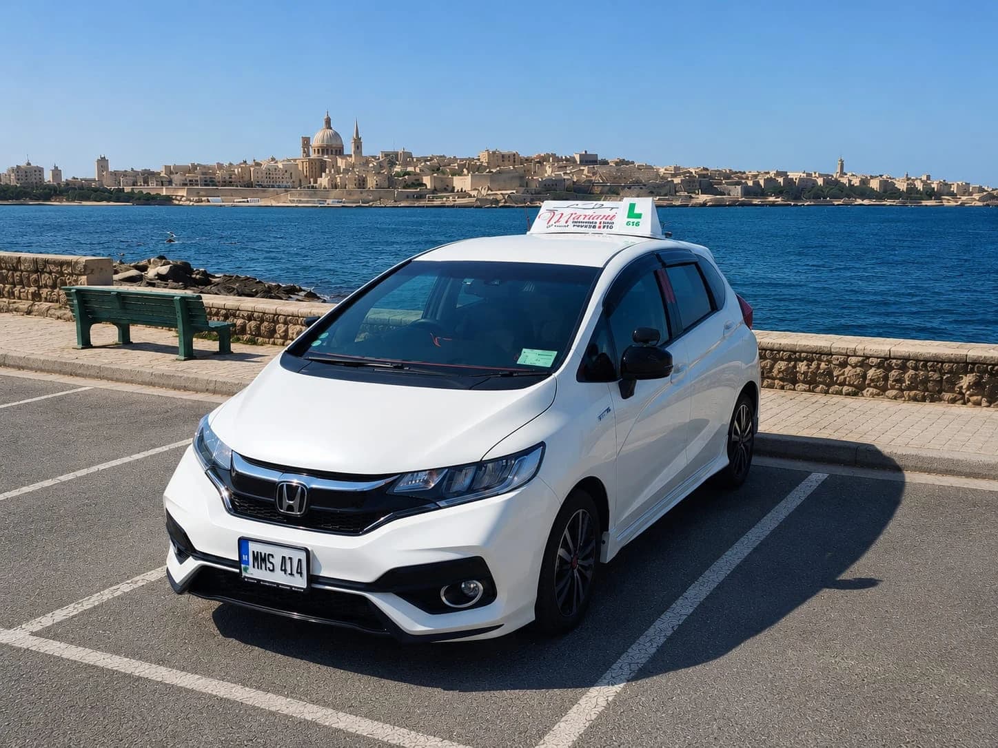 White Mariani Honda learner car parked by the waterfront with Valletta in the background